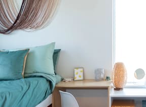 a bedroom with a bed and a desk in front of a window at Society 62 Apartments, Portland, OR, 97213