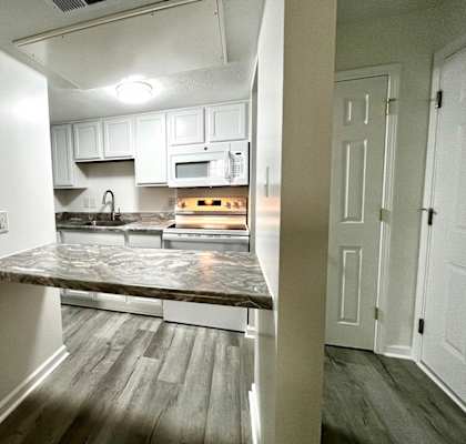 A kitchen with a marble countertop and white cabinets.