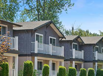 A row of houses with balconies and trees in front.
