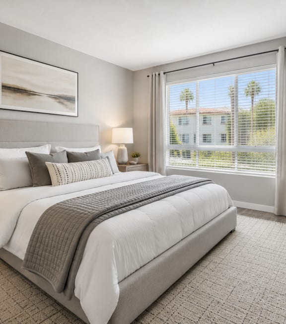 A well-lit bedroom with a large bed, two lamps, and a framed picture on the wall.