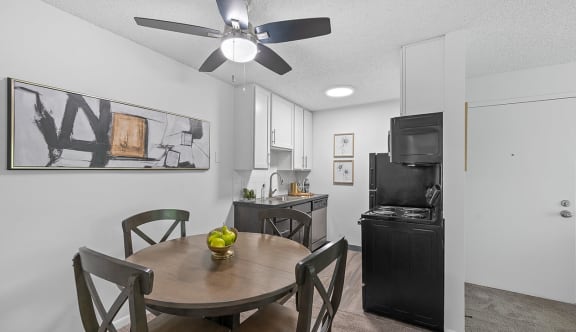 a dining room and kitchen with a table and a ceiling fan