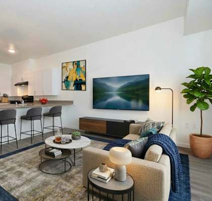 A modern living room with a kitchen area in the background.