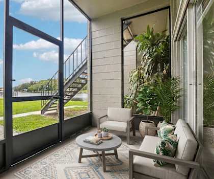 A balcony with a table and chairs overlooking a green lawn.