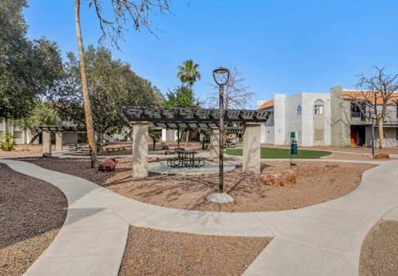 A park area with a bench and a tree in front of a building.