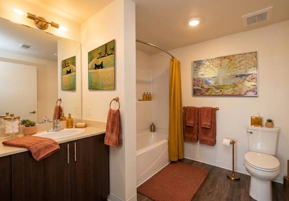A bathroom with a toilet, sink, and a painting on the wall.