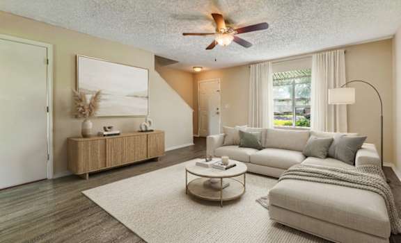 A living room with a grey sofa, a coffee table, and a ceiling fan.
