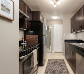 A kitchen with dark brown cabinets and black countertops.