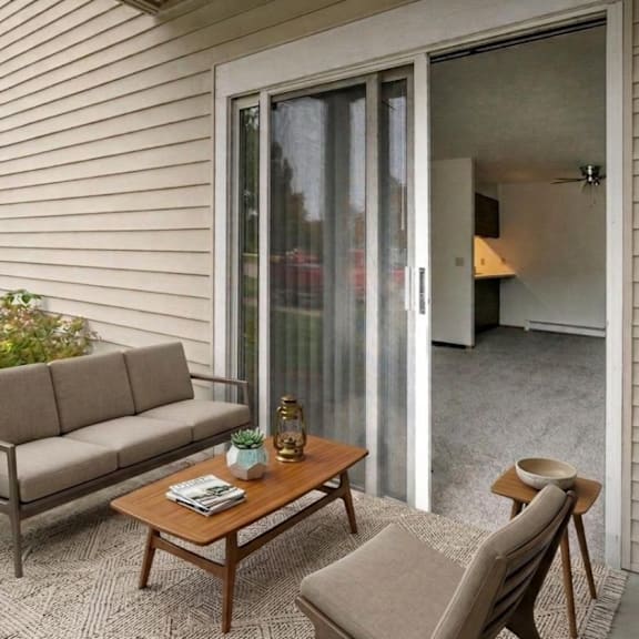 A patio with a couch, chair, and table.