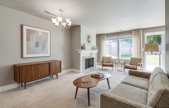 A living room with a fireplace, chairs, and a painting on the wall.