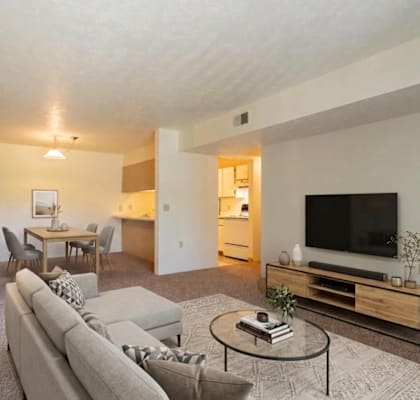 A living room with a grey couch and a glass coffee table.