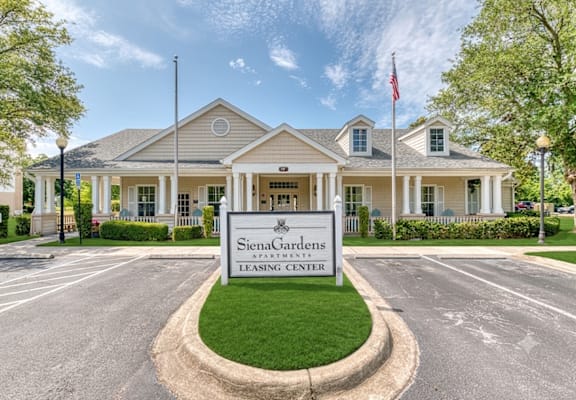 A large building with a sign that says Siena Gardens Apartment Leasing Center.