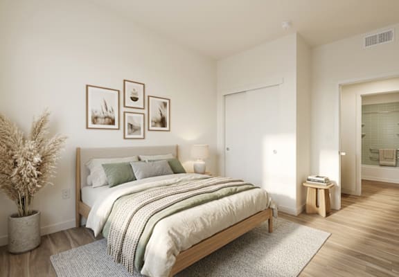 A bedroom with a large bed and a potted plant.