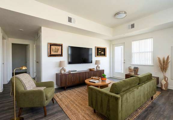 A living room with a green couch, a chair, and a coffee table.