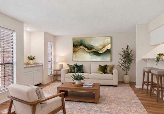 A living room with a white couch, a wooden chair, a coffee table, and a painting on the wall.