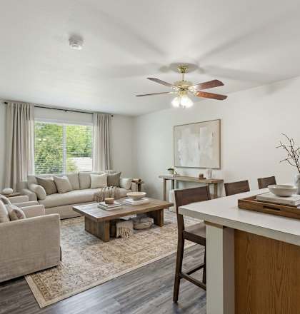 A well-lit, spacious living room with a kitchen area in the background.