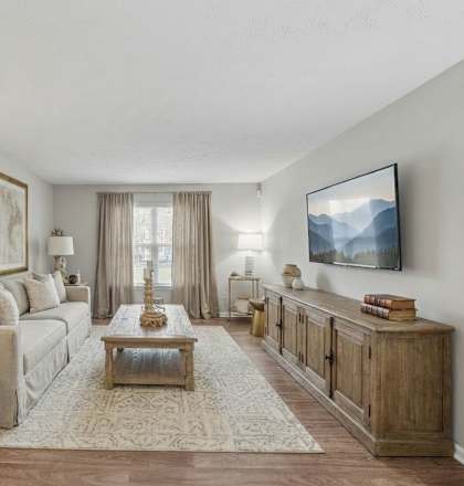 A living room with a couch, a coffee table, and a TV mounted on the wall.