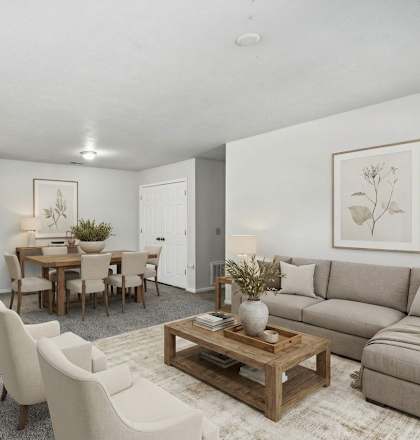 A living room with a grey couch, a wooden coffee table, and a dining table with chairs.