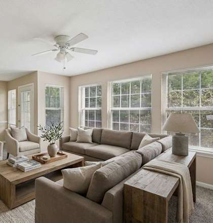 A living room with a large couch, a coffee table, and a ceiling fan.
