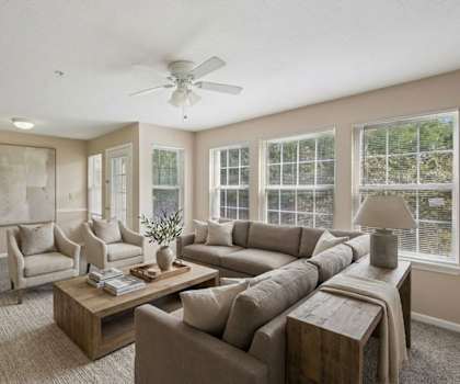 A living room with a large couch, a coffee table, and a ceiling fan.
