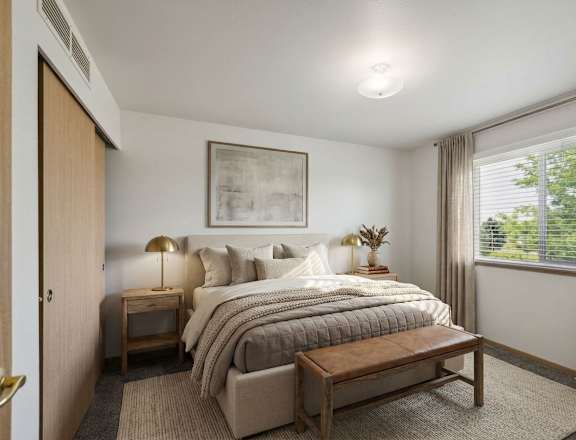 A bedroom with a large bed and a wooden nightstand.