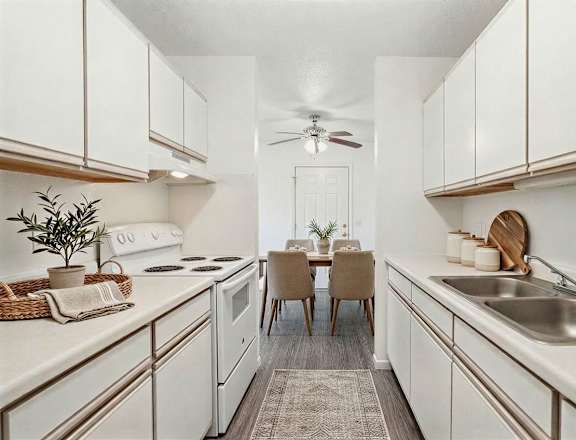 A kitchen with white cabinets and a dining table with chairs.
