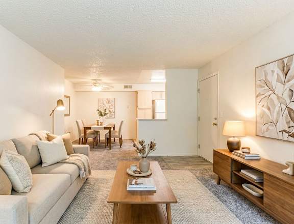 A living room with a couch, coffee table, and a dining table.