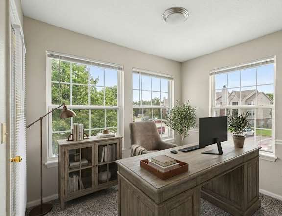 A home office with a desk, chair, and a window overlooking a residential area.