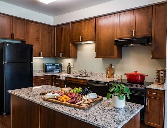 A kitchen with a black refrigerator and wooden cabinets.
