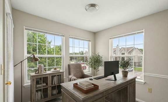 A home office with a desk, chair, and a window overlooking a residential area.