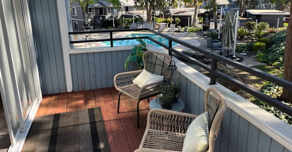 a balcony with two wicker chairs and a swimming pool