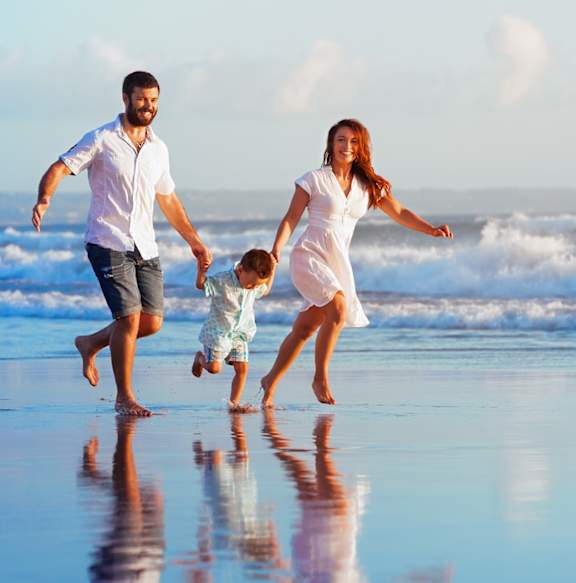 A family of three is running on the beach.
