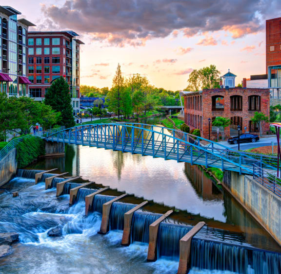 a bridge over a river with a waterfall in a city