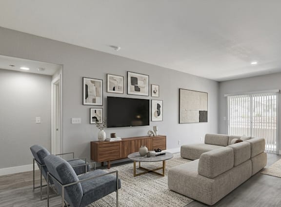 A living room with a grey couch, a blue chair, a wooden cabinet, a television, and a potted plant.