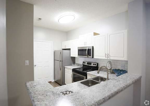 A kitchen with granite countertops and white cabinets.