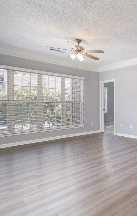 A spacious room with a ceiling fan and wooden flooring.