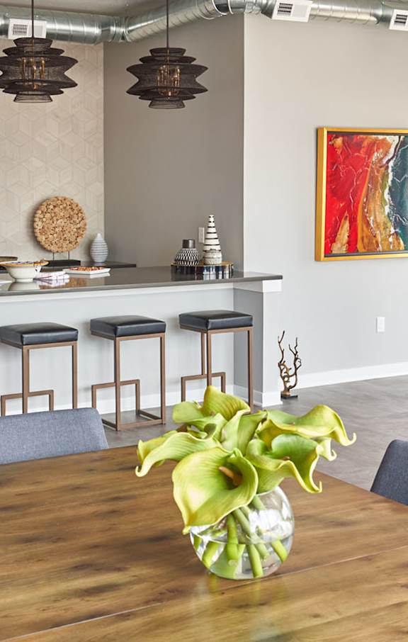 a dining room with tables and chairs and potted plants at Vue Apartments, Des Moines, Iowa
