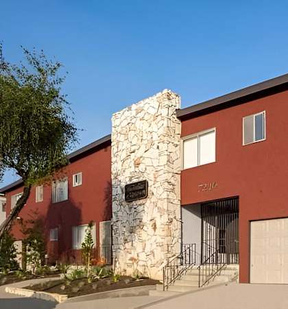 a red building with a stone chimney and two garage doors