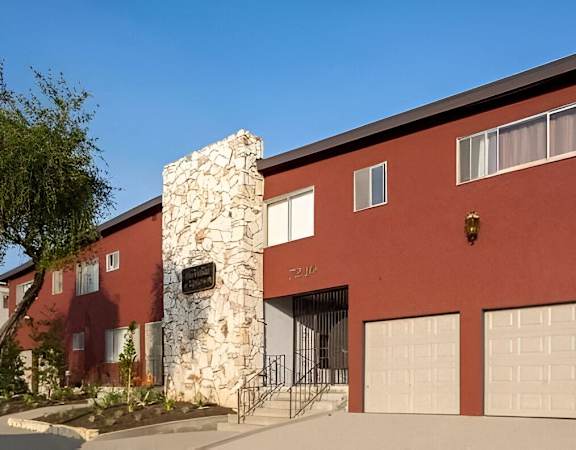 a red building with a stone chimney and two garage doors