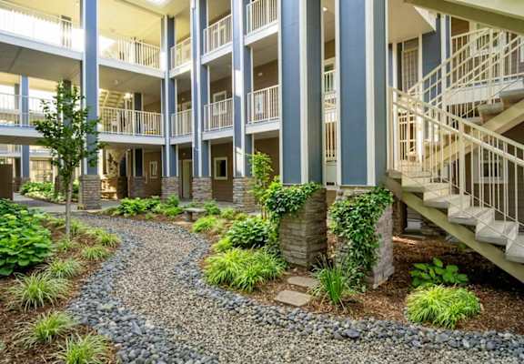 A gravel path leads to a building with a staircase.
