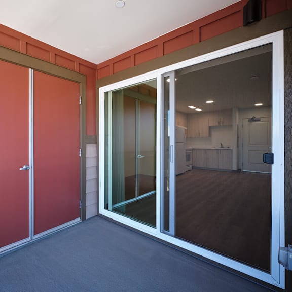 A room with a red door and a glass door leading to another room.