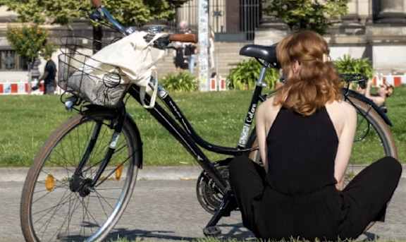 a woman sitting on the grass next to a bike