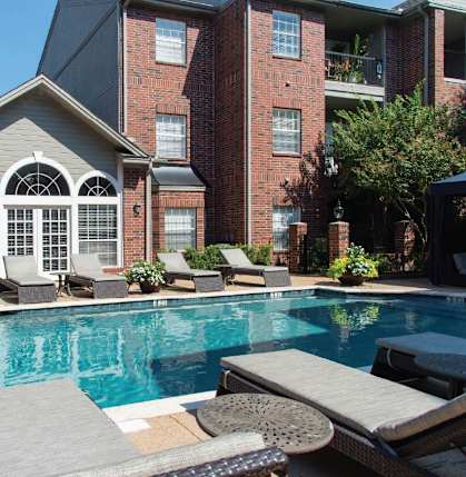 A pool with a table and chairs in front of a building.