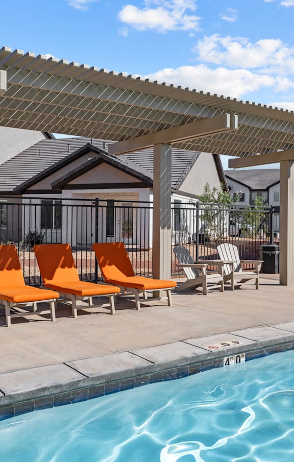 A pool with a pergola and chairs.