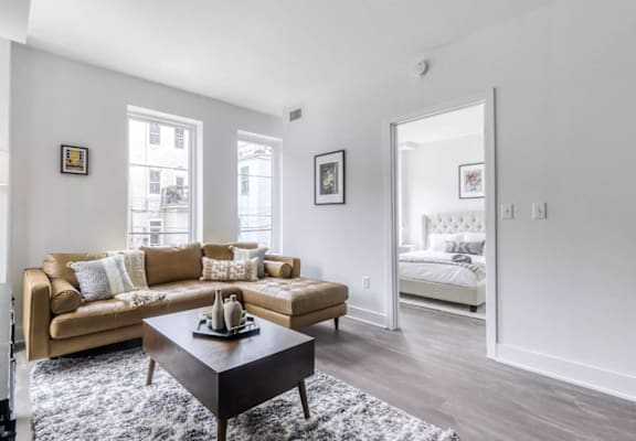 a living area with a couch coffee table and a doorway into a bedroom