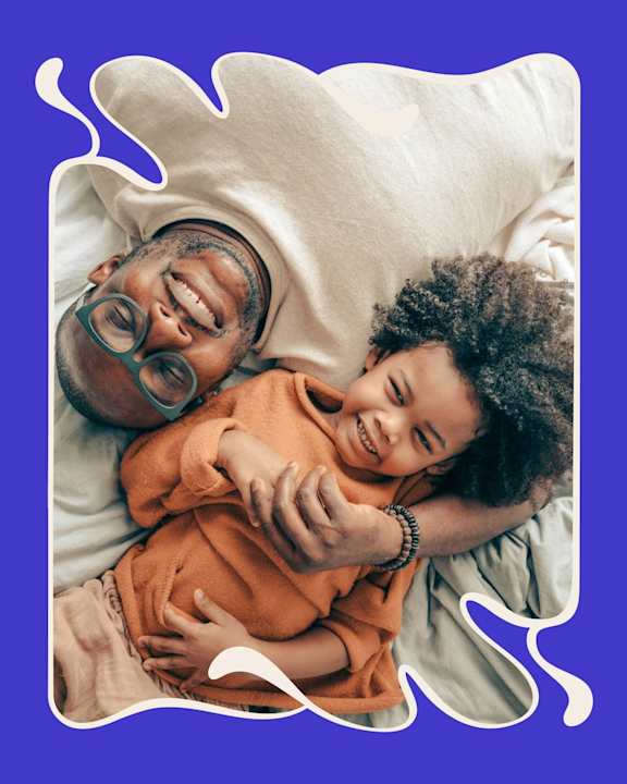 A man and a child are lying down, smiling and cuddling at Fernlow Apartments, Houghton Regis