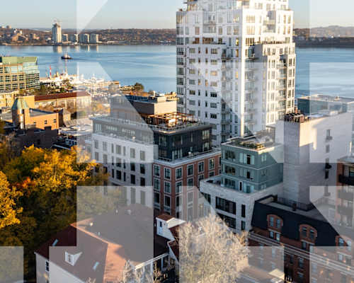 A cityscape with a large building in the foreground and a body of water in the background.