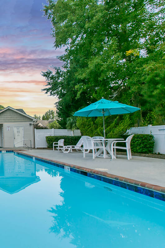 A swimming pool with a building and trees in the background.