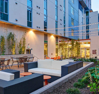 a patio with a couch and tables in front of a building
