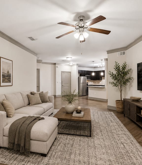 A living room with a white couch, a coffee table, and a flat screen TV mounted on the wall.
