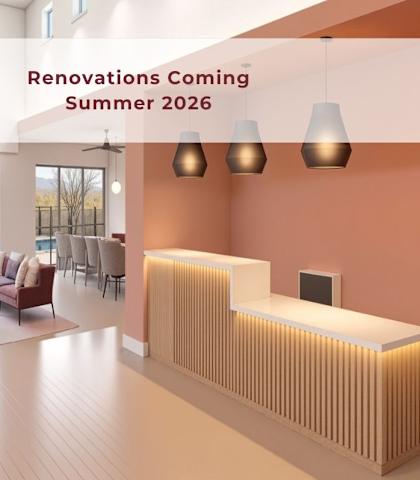 A modern living room with a large window overlooking the desert and a sign that reads "Renovations Coming Summer 2026".